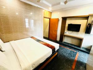 a bedroom with a bed and a flat screen tv at HOTEL TEJASRI RESIDENCY in Vijayawāda