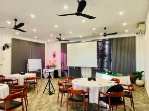 uma sala com mesas e cadeiras e um ecrã de projecção em Sea Breeze Resort em Sihanoukville