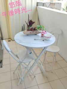 Qianshun Homestay في Xingang: طاولة بيضاء مع كرسيين وطاولة مع ورد
