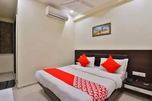 um quarto com uma cama grande e almofadas vermelhas e brancas em HOTEL KHUSHBOO em Ahmedabad