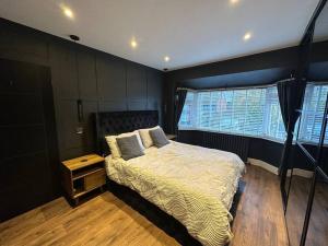 a bedroom with a bed and a nightstand and two windows at Luxury 3 bed coastal house in North Tyneside