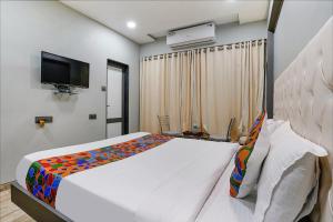 ein Schlafzimmer mit einem Bett und einem TV in der Unterkunft FabHotel Grand Inn II in Navi Mumbai