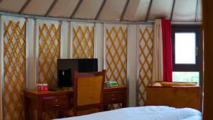 1 dormitorio con 1 cama, escritorio y TV en APEX Le Yurt Skardu en Skardu