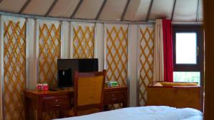a bedroom with a bed and a desk and a tv at APEX Le Yurt Skardu in Skardu