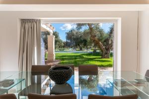 einem Esstisch aus Glas mit einer Vase darüber in der Unterkunft Trullo Brenda By Raro Villas in San Michele Salentino