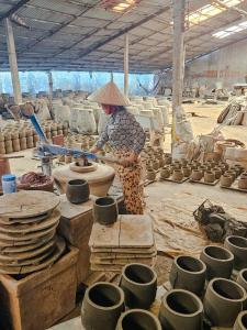 a woman is making pottery in a room with pots at Sông Mê Home in Vĩnh Long