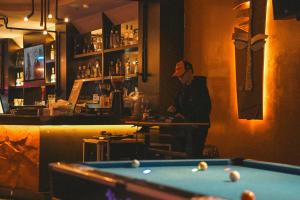 a man standing at a bar with a pool table at The One Hostel Hanoi in Hanoi