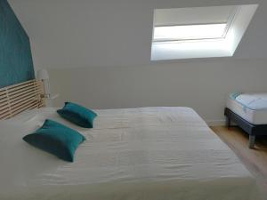 a large white bed with two green pillows on it at Room in Guest room - Decouvrez un sejour relaxant a Meursault, en France in Meursault