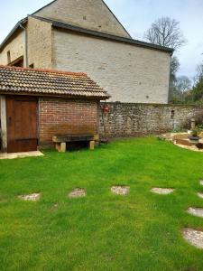 a yard with a brick building and a bench at Room in Guest room - Decouvrez un sejour relaxant a Meursault, en France in Meursault