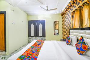 1 dormitorio con 1 cama blanca grande con almohadas coloridas en FabHotel Golden Horizon en Ranchi