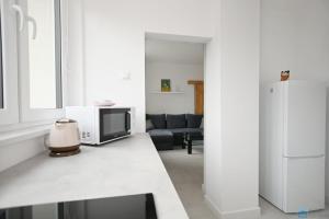 a white living room with a couch and a refrigerator at Bianco by 3City Rentals in Sopot