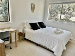a bedroom with a bed with white sheets and a window at Bayview Oasis- With pool in Hardys Bay