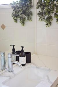 a bathroom sink with two bottles of soap and a mirror at Bayview Oasis- With pool in Hardys Bay