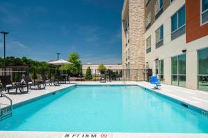 a swimming pool with tables and chairs next to a building at Holiday Inn Express & Suites Griffin in Griffin