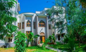 a large white building with trees in front of it at Amani House in Kilifi