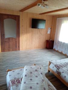 a room with two beds and a flat screen tv at Sadyba u Vani in Volovets