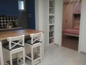 uma cozinha com uma mesa de madeira e 2 bancos brancos em Appartamento Super Confortevole em Gaglianico