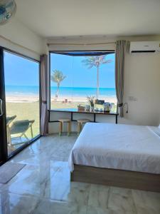 a bedroom with a bed and a view of the beach at Baan Be Beach in Lang Suan
