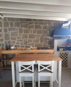 uma cozinha com uma mesa de madeira e 2 cadeiras brancas em Appartamento Super Confortevole em Gaglianico