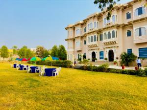 a building with tables and umbrellas in front of it at Jag Aravali Resort Udaipur- Experience Nature away from city Hustle in Udaipur