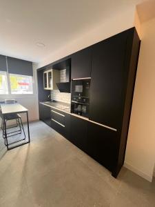 a kitchen with black cabinets and a table in it at Jacuzzi & Relax Almería Juzgados in Almería