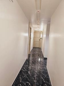 un pasillo vacío con suelo de mármol negro y paredes blancas en HOTEL R K VILLA en Ahmedabad