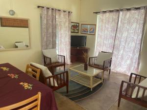 a living room with chairs and a table and a tv at Les Varangues Rodrigues in Rodrigues Island