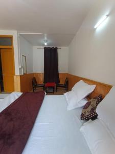 馬拉里的住宿－iSaint's Kuteer，一间卧室配有带白色床单和枕头的床。