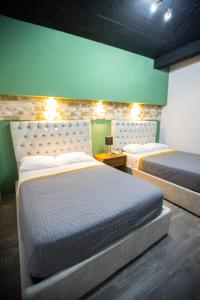 1 dormitorio con 2 camas y pared verde en Casa Maria Jimena Hotel Boutique, en Chihuahua