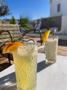 een drankje met een sinaasappelschijfje op een tafel bij uma casa em entradas guesthouse in Entradas