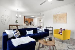 ein Wohnzimmer mit einem blauen Sofa und einem gelben Stuhl in der Unterkunft CozySuites by stadium with pool, gym, & kombucha! in Glendale