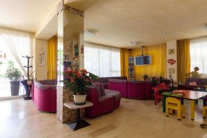 a living room with purple furniture and a table at Hotel Singapore in Milano Marittima