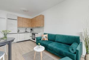 a living room with a green couch and a kitchen at Modern Apartment 1 Maja with Parking in Kołobrzeg by Rent like home in Kołobrzeg