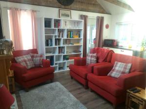 a living room with two red chairs and a book shelf at The Little House in Hull in Hull