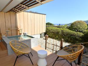 a patio with two chairs and a swimming pool at Seizan Yamato in Ito