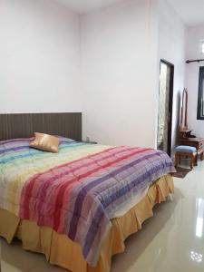 a bedroom with a bed with a colorful blanket at Villa Mawar Bumi Citeko in Bogor