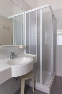 a white bathroom with a sink and a shower at Hotel Singapore in Milano Marittima