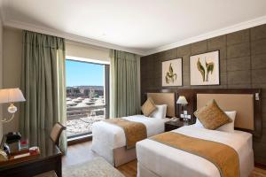 a hotel room with two beds and a window at The Biltmore Al Madinah بيلتمور المدينة in Al Madinah
