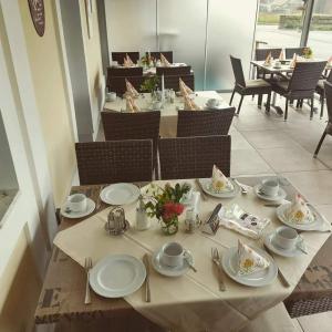 - une table avec des assiettes et des ustensiles dans un restaurant dans l'établissement Hotel & Frühstückspension Raabtal, à Feldbach