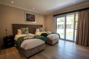a bedroom with two beds and a sliding glass door at Arebbusch Travel Lodge in Windhoek +74 photos