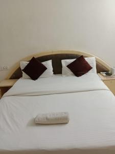 a large white bed with a towel on it at Hotel Cozy Residency in Jabalpur
