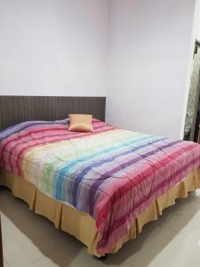 a bed with a colorful blanket on top of it at Villa Mawar Bumi Citeko in Bogor