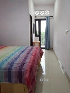 um quarto com uma cama com um cobertor colorido em Villa Mawar Bumi Citeko em Bogor