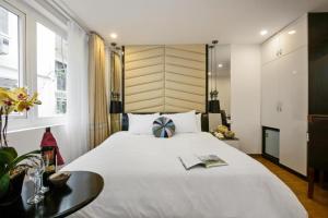 a bedroom with a large white bed and a table at Splendid Holiday Hotel Spa in Hanoi
