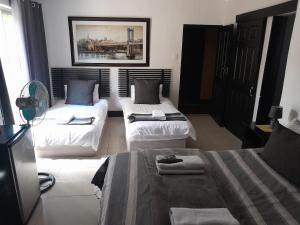 um quarto de hotel com duas camas e uma televisão em Robert's Place Paarl em Paarl
