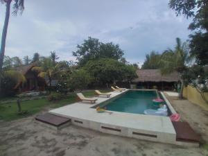 a swimming pool with lounge chairs in a backyard at Gita Gili Bungalow in Gili Air