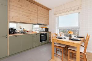 a kitchen with a wooden table with chairs and a dining room at 9th Floor Green and Grey Apartment in Gdańsk Brzeźno with Two Bedrooms and Parking by Renters in Gdańsk