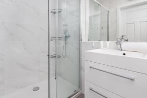 a white bathroom with a shower and a sink at 9th Floor Green and Grey Apartment in Gdańsk Brzeźno with Two Bedrooms and Parking by Renters in Gdańsk
