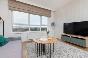 a living room with a coffee table and a flat screen tv at 9th Floor Green and Grey Apartment in Gdańsk Brzeźno with Two Bedrooms and Parking by Noclegi Renters in Gdańsk