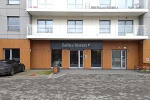 a building with a car parked in front of it at 9th Floor Green and Grey Apartment in Gdańsk Brzeźno with Two Bedrooms and Parking by Noclegi Renters in Gdańsk